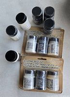 Loose bottles and sealed blister packs of Distress Crackle Paint in black and white along with crackle additive bottles displayed on flat surface.