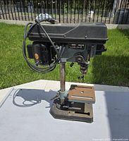 Side angle showing motor housing, vertical adjustable column, base, and worktable with clamp slots