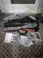 All components of the EMART background stand, including metal rods, carrying bag, and assembly parts laid out, some wrapped in plastic.