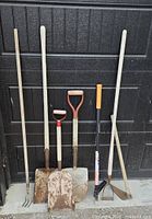 Photo showing seven gardening tools including three shovels, a garden fork, two digging tools, and a weed cutter, arranged against a black backdrop.