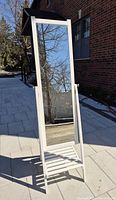 Front angled view of the IKEA ISFJORDEN standing mirror showing full white frame and clear glass reflecting outdoor scene.