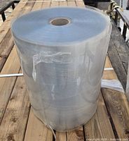 Front angle view of a large roll of thick clear plastic sheeting showing the outer layer and cardboard core.