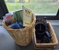 Two woven wicker baskets and assorted boxed and packaged office supplies inside one basket, including Post-it notes, pens, pencils, and markers, displayed on a white surface by a window.