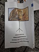 User manual showing a leopard photo on the front cover and text in multiple languages including English, German, French, and Russian.
