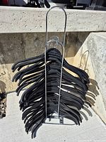 Front view of chrome standing hanger holder loaded with black hangers, showing the metal frame and structure in outdoor light.