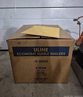 Closed cardboard box with label showing ULINE Economy Bubble Mailers #2 Gold size 8.5x12 with 100 mailers originally