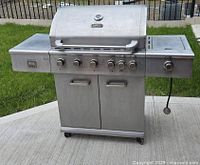 Full front view of assembled stainless steel grill with hood closed and side shelves