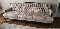 Full view of vintage floral antique couch with wooden frame and tufted backrest