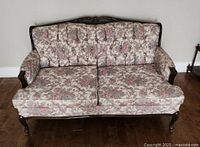 Front view of the vintage couch showing floral upholstery and carved wood frame