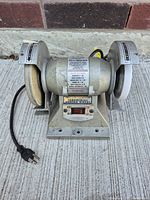Front view of Wolff Industries bench grinder showing 5" grinding wheels, power cord, and on/off switch.