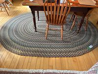 Oval braided rug under wooden table showing overall shape and color