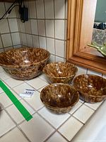 Four Bennington pottery bowls in Rockingham style glaze arranged on tiled countertop