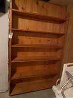 Full view of large pine bookcase with five shelves showing overall structure and wood finish.