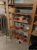 Overall lot view of shelves with apple baskets, hummingbird feeders, wire basket, and plant cages
