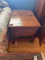 Full view of rectangular wooden side table placed next to couch and other furniture, showing top and legs.