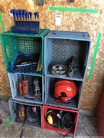 Overview of lot showing stacked milk crates containing tools, safety gear, saw blades, and metal hardware parts