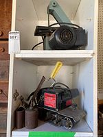 Shelf with a Delta belt sander on the upper shelf and Sears Craftsman belt sander with sanding bow and sanding sleeves on the lower shelf.