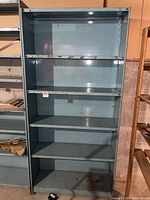 Front view of the metal shelving unit showing four shelves with visible rust and wear marks.