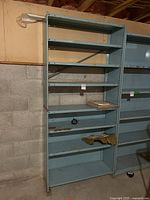 Front view of blue metal utility shelving unit with 6 shelves, showing wear and rust marks.