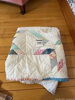 Quilt folded on floor showing patchwork pattern and colors.