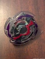 Top view of Beyblade Burst Doomscizor showing purple and red scissor-shaped design with clear outer ring.