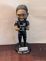 Front view of Derel Walker bobblehead showing detailed face, black Toronto Argonauts jersey with number 87, holding a football, standing on a base with name and logo plaque.