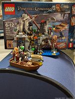 Full view of the LEGO Pirates of the Caribbean set 4181 Isla De Muerta, assembled with minifigures and accessories in front of the box showing set details.