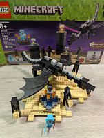 Full view of the assembled LEGO Minecraft Ender Dragon, base platform, small build, and minifigures in front of the LEGO box