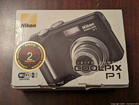 Top/front side of original Nikon Coolpix P1 camera box showing camera image, brand and model info, and 24 months warranty label along with WiFi certified logo.