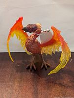Front and side view of new Safari LTD phoenix figure with tag attached, showing detailed feathers and bright wing colors.