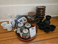 Full overview of all tea and sake sets including kyusu teapot with cups, sake bottle with cups, creamer, black ceramic cups, and brown ceramic cups stacked