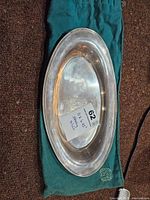 Oval Birks sterling silver tray displayed on green drawstring bag