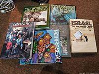 Five nonfiction hardcover books on the floor with visible titles and cover art.