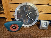All three clocks shown together on floor, including large weather station clock and two small clocks
