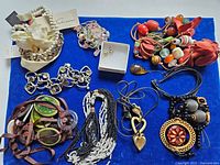 Overview of 10 jewelry pieces on blue background including bracelets, necklaces, earrings of various materials and colors