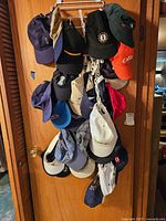 Hats hanging on a wooden door including various branded sports caps