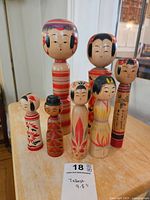 Full view of seven Japanese Kokeshi dolls arranged on a wooden surface