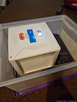 White Lite Brite unit inside plastic tote, showing the screen and grid on top with speakers on sides.