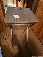 Full view of table showing wood-grain tabletop, foldable metal legs, and electric cord.