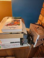 Photo showing stacked boxes containing manuals, film reels, and an 8mm movie editor device on top of the boxes next to a brick wall.