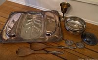 Photo showing the full set arranged on a wooden table, including the silverplate tray, chalice, bowl, decanter labels, and wooden salad servers.