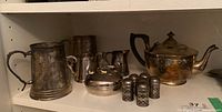 Group photo of silverplate items including teapot, tankard, creamers, sugar bowl, and six shakers.