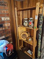 Front view of wood shelf unit with various items placed on shelves (not included in lot). Shelf against wood-paneled wall.