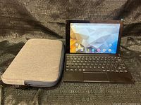 Tablet with keyboard open next to grey sleeve