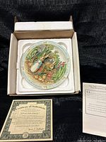 Plate in styrofoam insert inside original box with COA and paperwork visible