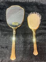 Front view of hand mirror and hairbrush showing gold finish and bristles