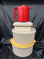 Stacked view: red pitcher atop square and two round containers