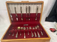 Open chest showing full complement of knives, forks and spoons in red-lined interior