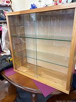 Front view showing wood frame, sliding glass doors, two glass shelves