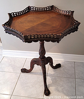 Full view of the antique octagonal wooden table showcasing the top, gallery edge, pedestal, and claw feet.